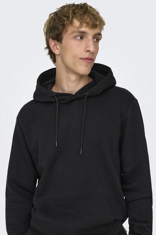 Man met blonde haren, close-up, draagt een zwarte hoodie met capuchon en touwtjes.