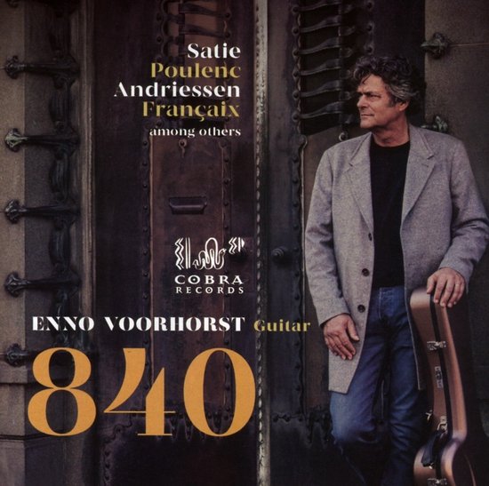 Enno Voorhorst, gitarist, staat met een gitaarkoffer naast een deur. Tekst: Satie Poulenc Andriessen Français among others.