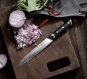 20 cm vleesmes met zwart handvat, met damascuspatroon, op een houten snijplank met gesneden ui en rode pepers.