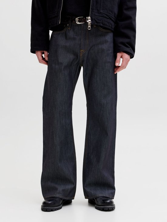 Detail van de voorkant van een donkerblauwe jeans met wijd uitlopende pijpen en gele stiksels.