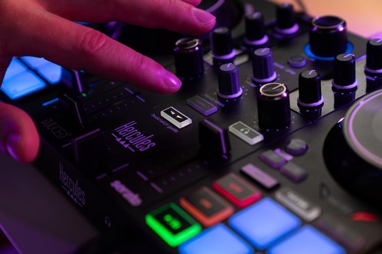 Hand op de Hercules DJ-controller, met focus op de verlichte knoppen en draaiknoppen.