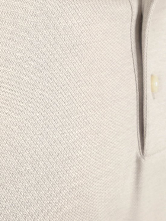 Close-up van de textuur en een knoop van een beige poloshirt.