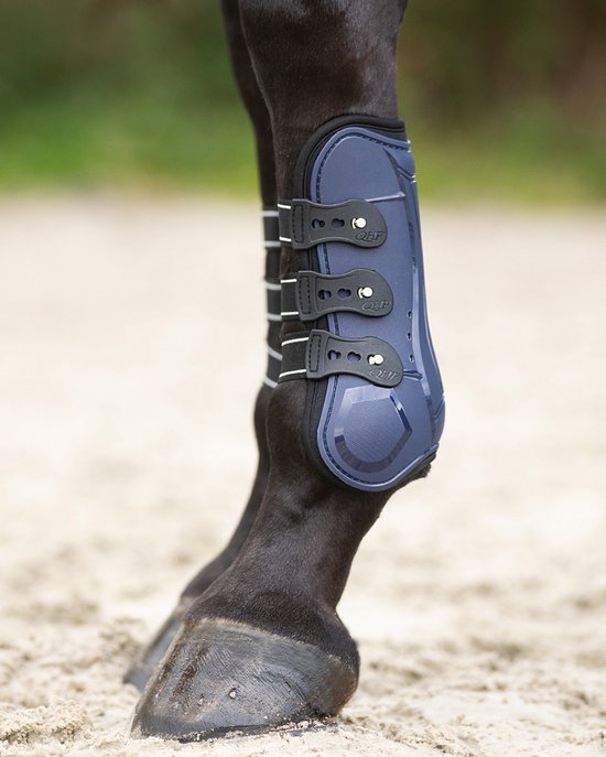 Donkerblauwe peesbeschermer met zwarte bandjes met witte strepen, om een paardenbeen.