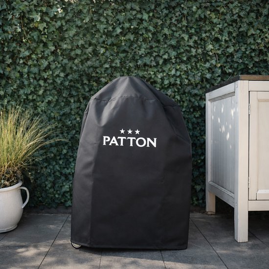 Zwarte kamado barbecuehoes met 'PATTON' logo, buiten op een terras bij een tuinkast.