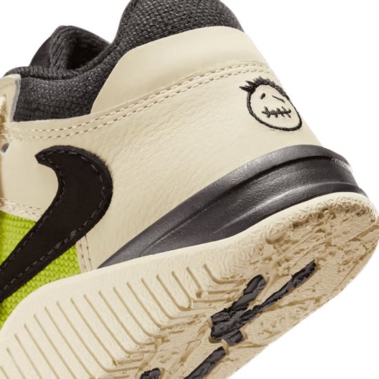 Detail van de beige sneaker met limegroene stof en geborduurde smiley.
