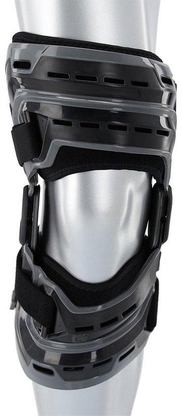 Grijze kniebrace met zwarte banden, scharnierend en met ventilatieopeningen.