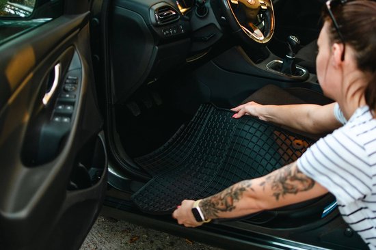 Vrouw met tatoeages legt een zwarte automatt in de auto.