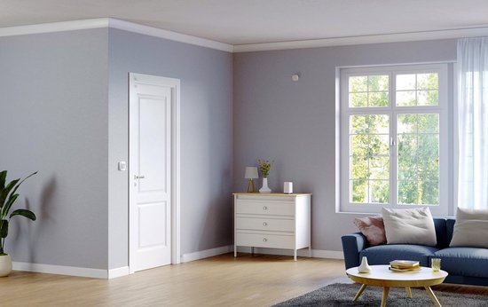 Woonkamer met een wit dressoir, een bank, een tafel en een raam. Rechts een witte Eufy Homebase.