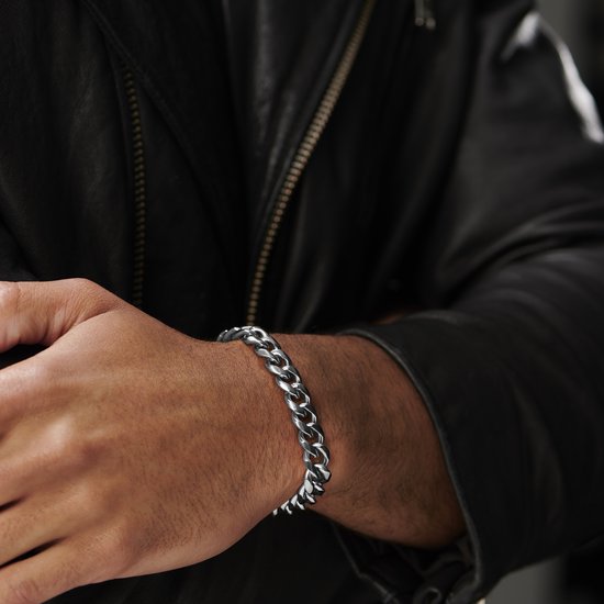 Dichtbij detail van een mannenarm met zilverkleurige schakelarmband om de pols.