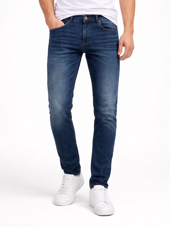 Man met een donkerblauwe slim fit spijkerbroek en witte sneakers.