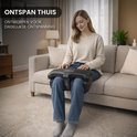 Een vrouw zit op een bank met het El Suvon voetmassageapparaat op haar schoot.