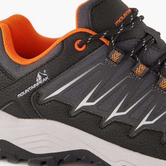 Detail van grijze wandelschoen met oranje voering, witte accenten en Mountain Peak logo.