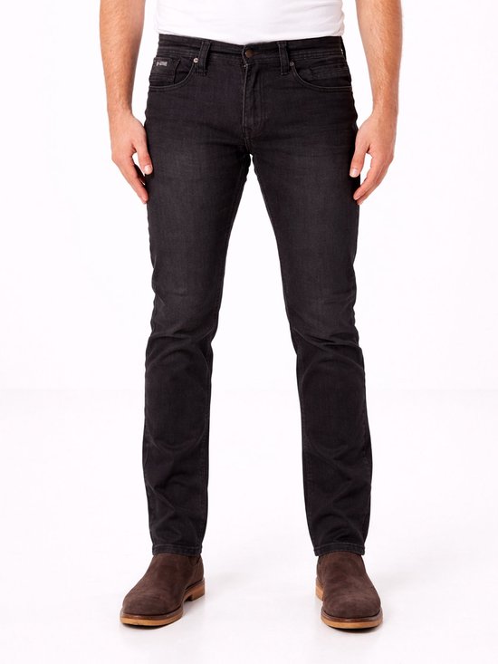 Man in zwarte slim fit jeans met een witte t-shirt en bruine schoenen.