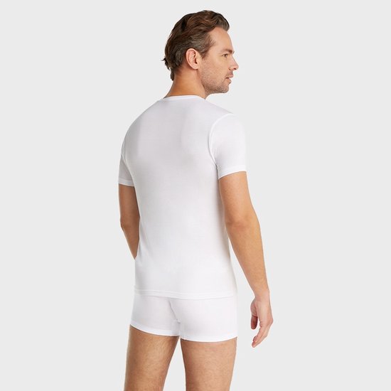 Man met donker haar, van achteren, in wit V-hals shirt en witte boxershort.