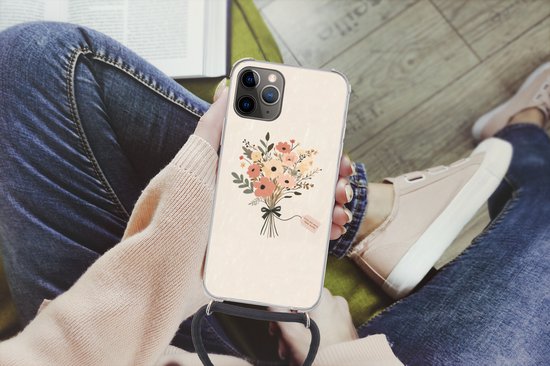 Persoon met telefoonhoesje met beige achtergrond en bloemenboeket. Hoesje met zwart koord gedragen crossbody.