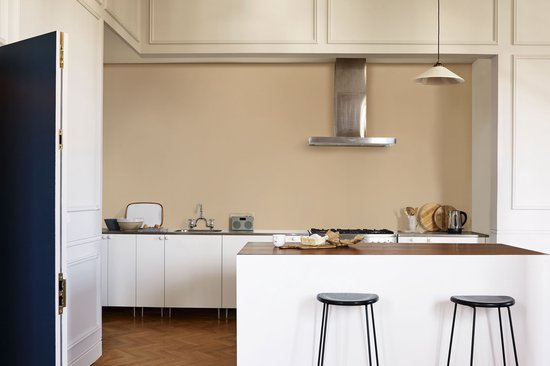 Keuken met witte kasten, een aanrecht, een kookplaat en een eiland met barkrukken, met een beige muur.