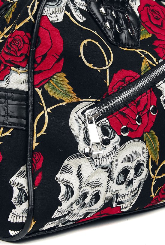 Close-up van een zwarte handtas met print van schedels en rode rozen. Rits met zilverkleurige ritslip.