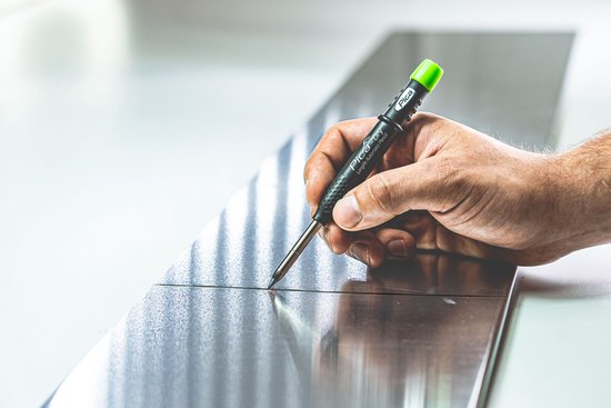Hand houdt Pica-Dry markeerstift met groene dop om te schrijven op een metalen oppervlak.