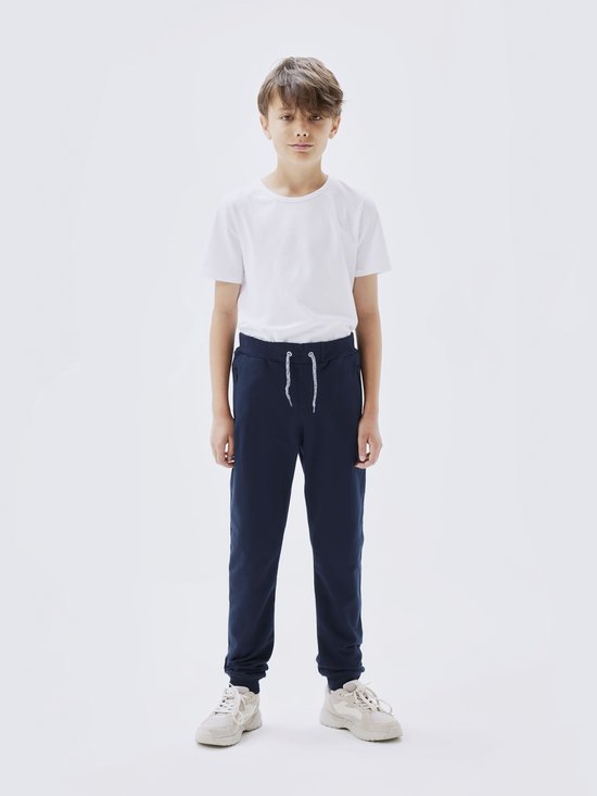 Jongen in een donkerblauwe joggingbroek met trekkoord en ritszakken.