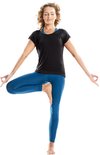 Vrouw in zwarte bamboe top en blauwe legging in boomhouding op witte achtergrond.