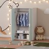 Open mintgroene kast met kleding en opbergdozen, in een kinderkamer.