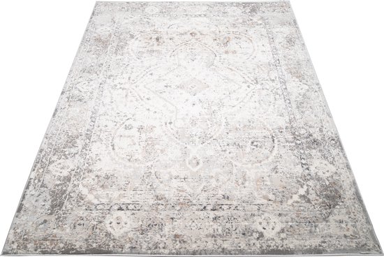 Un tapis vintage beige clair avec un motif détaillé dans des tons gris et marron.