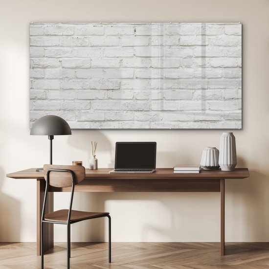 Acrylglas schilderij met witte baksteen textuur, hangend boven een bureau met laptop in een kantoorruimte.
