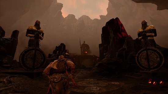 Kratos kijkt naar twee gouden standbeelden met schilden, in een duistere, rotsachtige omgeving.
