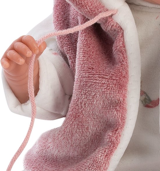 Close-up van de hand van babypop Mimi die speelt met een roze koordje van het vestje.