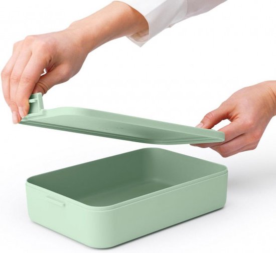 Mains retirant le couvercle d'une boîte à pain Brabantia vert jade.