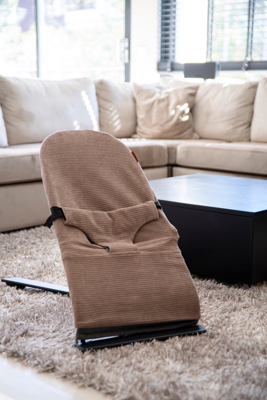 Bruin corduroy wipstoel op een beige vloerkleed in een woonkamer.