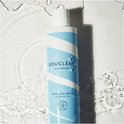 Fles hydraterende haarreiniger met blauwe en witte strepen, in water met golven en druppels.
