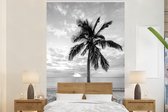 Behang - Fotobehang Palmboom op het strand bij zonsondergang - zwart wit - Breedte 200 cm x hoogte 300 cm