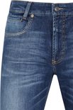 Detail van donkerblauwe jeans met lichte wassing en gele sierstiksels.