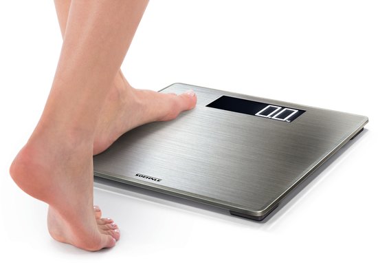 Een voet die een zilverkleurige digitale weegschaal betreedt. Display toont '0.0'.