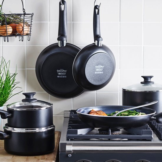 Keuken met GreenPan kookgerei: drie pannen hangen aan de muur, twee pannen en een stoofpan staan op het fornuis.