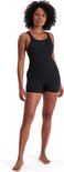 Vrouw in zwart Speedo sportbadpak met korte pijpen, staand.