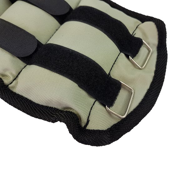 Detail van een grijs enkel- of polsgewicht met zwarte banden, velcro en gespen.