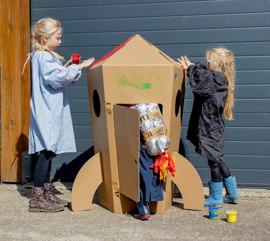 Twee kinderen versieren een kartonnen raket met verf. Een meisje schildert rode verf op de punt.
