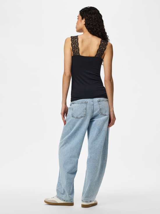 Model van achteren in zwarte top met kanten bandjes en lichte spijkerbroek.