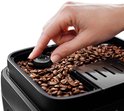 Hand draait aan knop 'Grinder Adjust' in reservoir gevuld met koffiebonen.