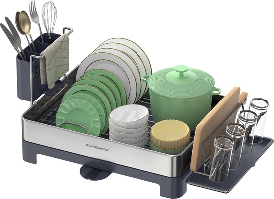 Un égouttoir gris et en acier inoxydable, rempli d'assiettes vertes et blanches, de tasses, d'une marmite, de verres et d'ustensiles de cuisine. Une planche à découper en bois est également présente.
