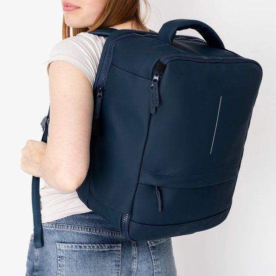 Donkerblauwe rugzak gedragen door een vrouw met spijkerbroek en wit T-shirt.