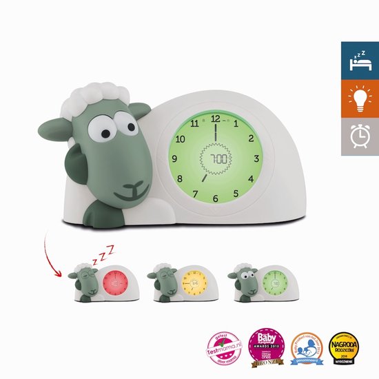 Wit schaap wekker met groene details, toont 7:00 op groene wijzerplaat. Kleine schaapjes tonen rode, gele en groene wijzerplaten.