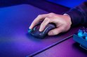 Een hand met een donkergrijs gamingmuis, met een scrollwiel en knoppen, op een zwart gamingmuismat.