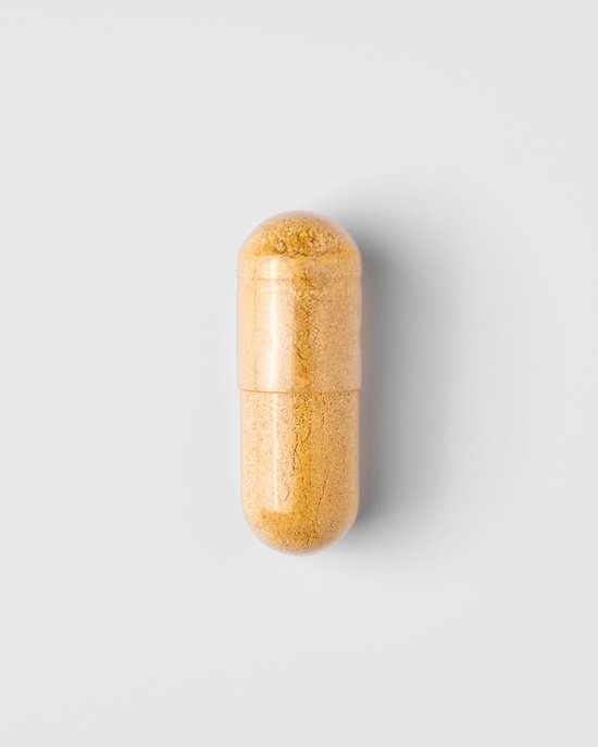 Een enkele gele capsule van Mattisson Vegan Multi Man op een witte achtergrond.