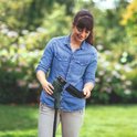 Vrouw met sproeten in een spijkerblouse monteert een onderdeel aan de groene Bosch grastrimmer.