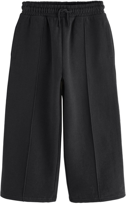 Zwarte wijde joggingbroek met deelnaden, elastische tailleband en trekkoord, op witte achtergrond.