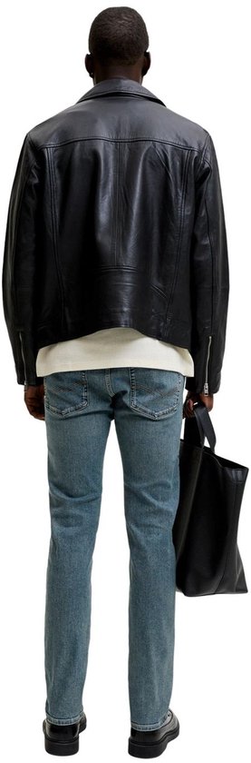 Achterkant van een man in blauwe slim fit jeans, zwarte jas en met een zwarte tas.