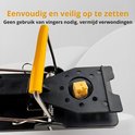 Zwarte muizenval met metalen veer, gele hendel en blokje kaas.